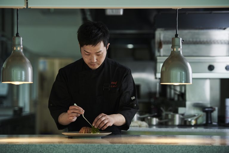 厨房のパスで皿を仕上げるシェフ